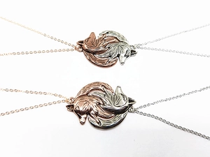 Close-up of interlocking fox pendant necklaces in silver and rose gold finishes