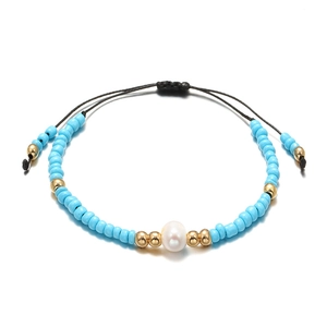 Detailed macro view of bohemian hand-woven bracelet with sky blue beads and freshwater pearl