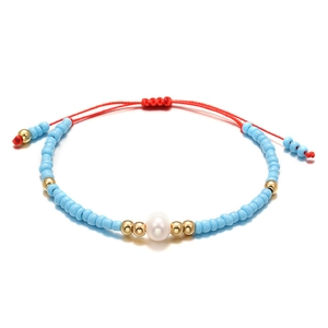 Detail of blue seed beads bracelet with gold accents and a white freshwater pearl centerpiece