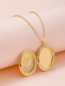 Macro detail of a golden oval locket necklace with internal floral relief and fine link chain