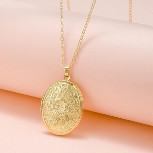 Detailed close-up of oval gold locket pendant with intricate floral embossing and hinge detail