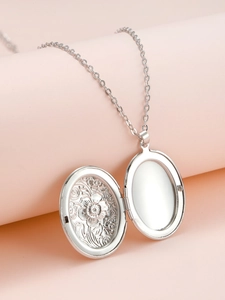 Detail of an open oval locket necklace showing a flower engraving and photo slot