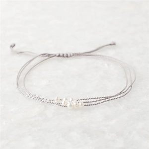 Détail du bracelet en cordon gris tressé avec perles d'eau douce naturelles et cordon ajustable