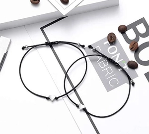 Close-up of adjustable woven heart bracelets for couples on a minimalist decorative background