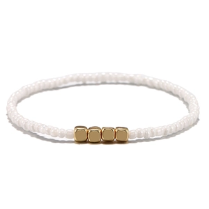Dettaglio del bracciale boho con perline bianche e quattro perle metalliche dorate a cubo