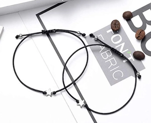 Detail of two handmade black woven bracelets with silver star pendants on white background
