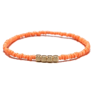 Dettaglio del bracciale bohémien con perline arancioni e piccoli cubi dorati