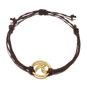 Detail of adjustable dark brown braided bracelet with a golden wave circular pendant