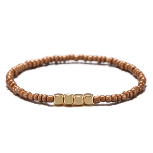 Dettaglio di bracciale boho con perline rotonde in rame e accenti quadrati dorati