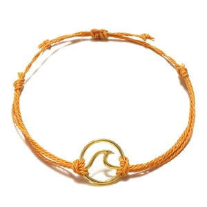 Detailed close-up of handmade orange woven surfing bracelet with gold wave charm