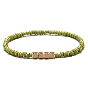 Bracciale bohémien con perline verde oliva e accenti cubici in metallo dorato su bianco