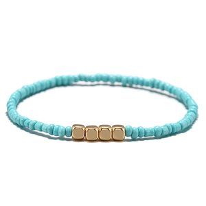 Dettaglio del bracciale con perline turchesi e accenti cubici in metallo dorato lucido