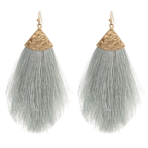 Detailaufnahme grauer Quastenohrringe mit gehämmerten goldenen Metallkappen im Boho-Stil