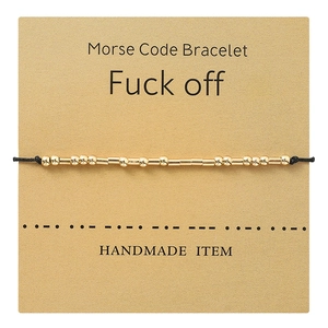 Morse Code golden bead bracelet with adjustable black cord on craft card display
