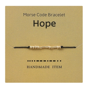 Close-up view of a handmade gold Morse code bracelet spelling Hope on its display card.