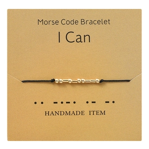 Detail of handmade Morse code bracelet with gold beads on display card showing 'I Can' message