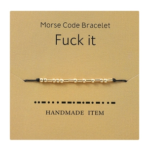 Handmade gold Morse Code Fuck it bracelet with black cord on gift presentation card