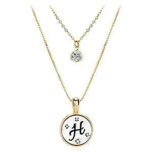 Detail of double-layered gold necklace featuring a zircon pendant and letter H shell charm
