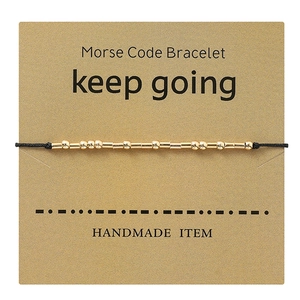 Detail of Morse code bracelet with gold beads on keep going inspiration card