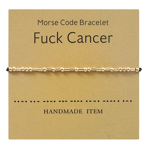 Detail of Morse code bracelet featuring gold beads and Fuck Cancer message card
