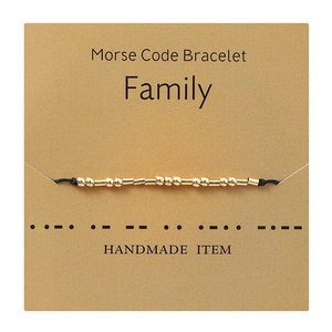 Detail of handmade Morse code family bracelet with gold beads on display card