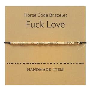 Detail of handmade Morse Code gold bead bracelet on Fuck Love kraft card display