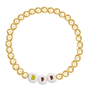 Detail of BFF gold beaded bracelet featuring white letter beads and metallic finish