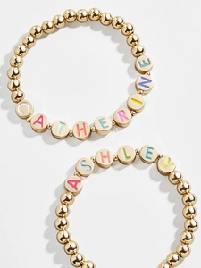 Détail de bracelets élastiques en perles dorées avec perles de lettres colorées pour Ashley