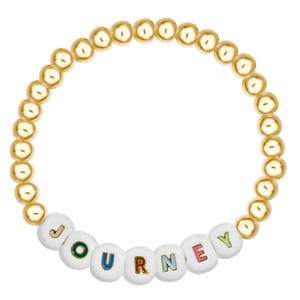 Detailed macro view of beaded bracelet with gold round beads and JOURNEY letter charms