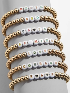 Stack of gold beaded bracelets with white letter beads showing LOVE and BE MINE text