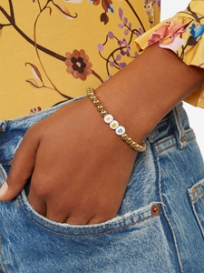 Detailed close-up of golden beaded bracelet with S and D letter charms and a smiley face