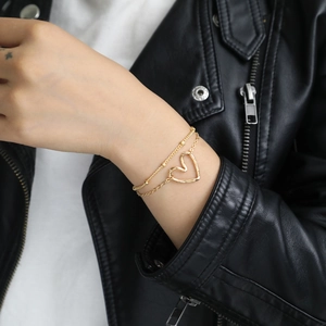 Minimalist double-layered gold heart pendant bracelet worn with a black leather jacket