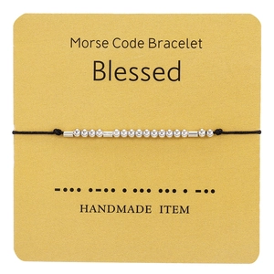 Close-up of Morse code bracelet featuring silver beads on yellow display card with text