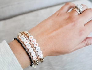 Detail of layered bracelets with custom name beads SAMUEL and CHARLES in gold and black