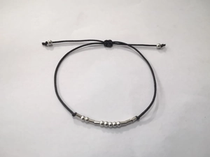 Detail of adjustable Morse code bracelet with silver beads and black wax rope texture