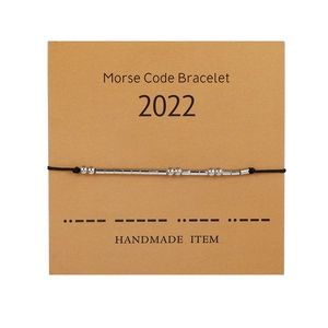 Pulsera código Morse hecha a mano en tarjeta kraft con cuentas plateadas y cordón