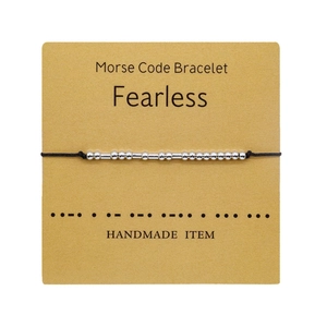 Pulsera de código Morse artesanal con mensaje Fearless sobre tarjeta de cartón amarillo
