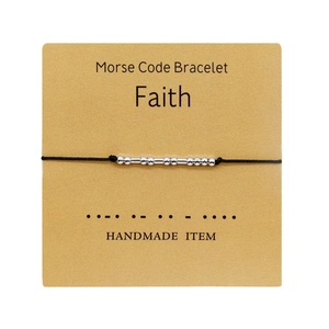Detalle de la pulsera Código Morse Faith con cuentas plateadas en cordón negro y tarjeta