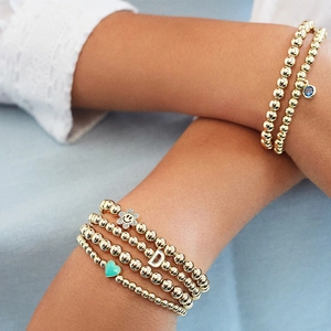 Bracciali elastici con sfere dorate e ciondoli a forma di faccina e girasole