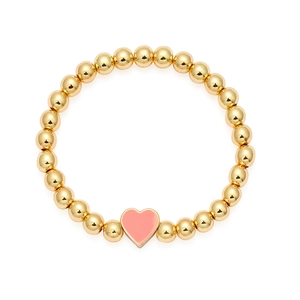 Dettaglio di un braccialetto di perle dorate con un ciondolo a forma di cuore rosa smaltato