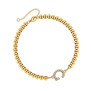 Close-up of a gold beaded bracelet with a sparkling crystal-encrusted letter C charm