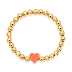 Dettaglio di un bracciale a sfere dorate con ciondolo a cuore rosa e finitura lucida