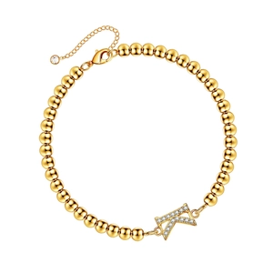 Macro detail of gold beaded bracelet featuring a sparkling zircon-encrusted letter K charm