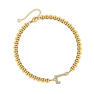 Detail of gold beaded bracelet featuring a crystal-encrusted letter L pendant and clasp
