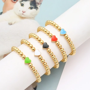Dettaglio di 5 braccialetti con perline dorate e cuori in smalto colorato su base bianca