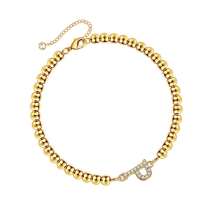 Detail of a gold bead bracelet featuring a pave-set crystal letter P charm and lobster clasp