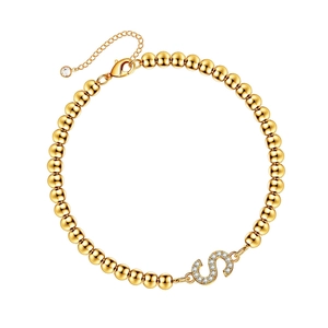 Macro shot of gold bead bracelet featuring a diamond-encrusted letter S pendant and clasp