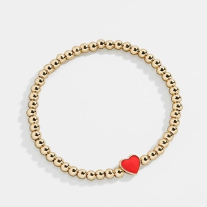 Bracciale a sfere dorate con ciondolo a cuore rosso brillante su sfondo bianco pulito