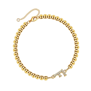 Golden beaded bracelet with a rhinestone-studded letter F pendant and lobster clasp