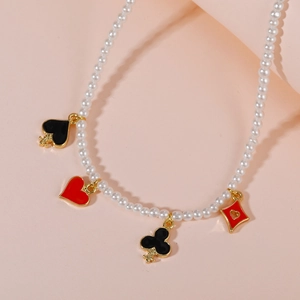 Elegante collar de perlas con cuatro dijes de póker sobre fondo melocotón suave